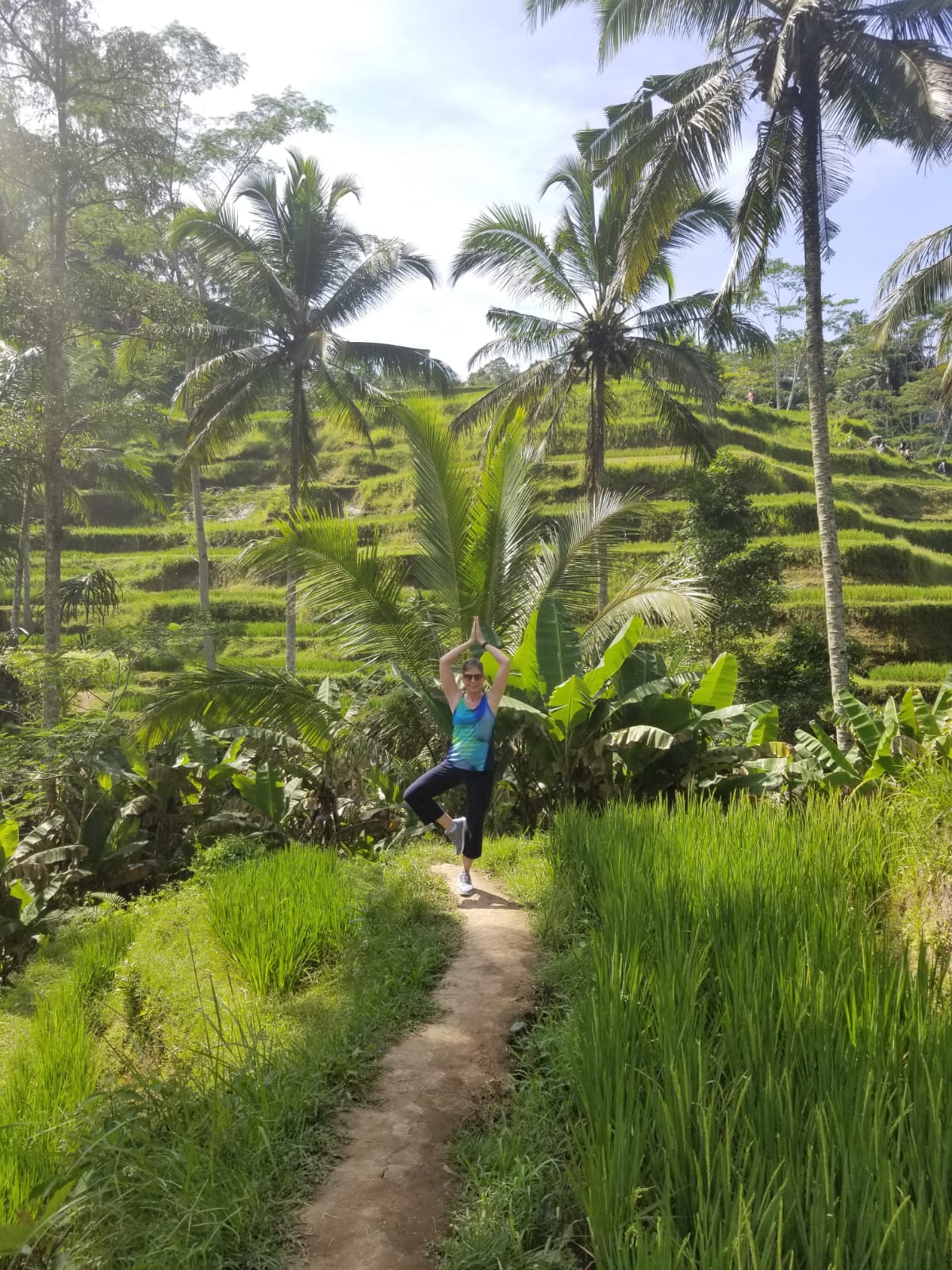 A woman is doing yoga in the middle of a lush green field.