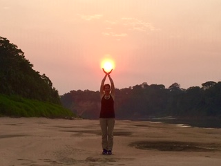 A woman standing on top of a sandy beach holding up an object.