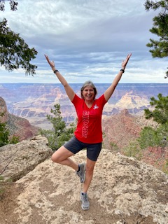 A woman standing on top of a mountain with her hands in the air.